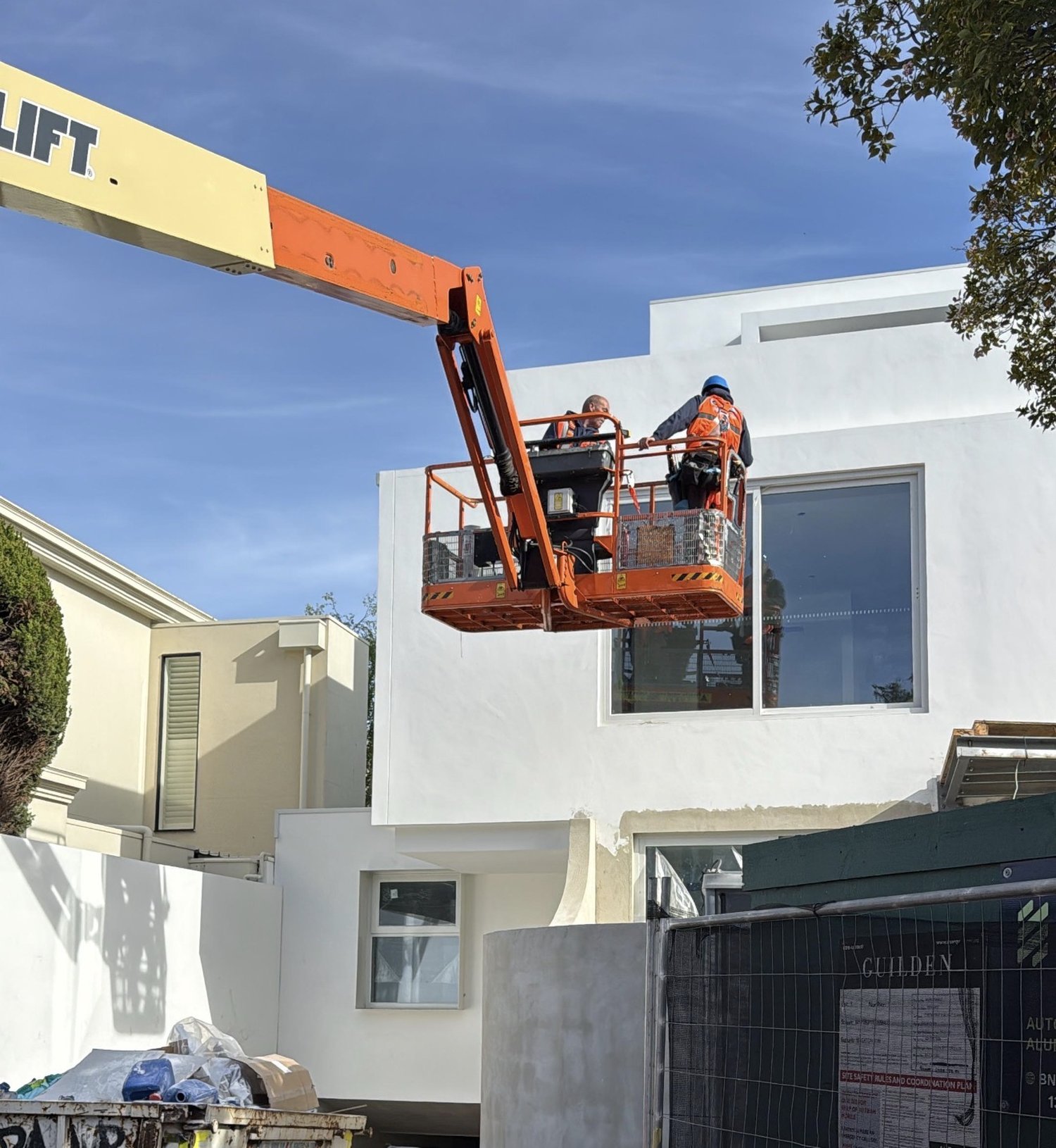 Pristine technicians on an EWP boom lift cleaning windows at a Melbourne construction site